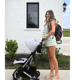 Person pushing a Colugo stroller in cool grey and wearing a diaper bag backpack in cocoa