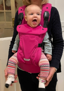 The Baby Carrier, Raspberry being worn by a parent